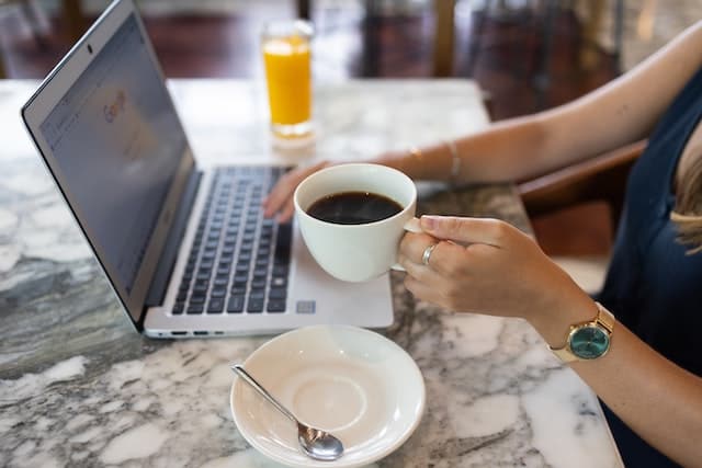 Frau mit Kaffee in der Hand am Laptop